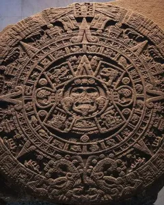 The Aztec Sun Stone carved as a large circular stone disc with a central face and concentric rings of symbols.