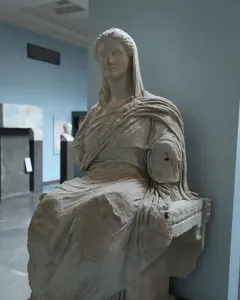 Demeter of Knidos seated marble statue with draped garments and missing forearms in a museum display