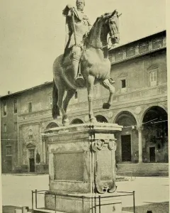 Ferdinando I de\' Medici equestrian statue on a stone pedestal in a public square with a historic building behind it.