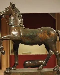 Bronze horse statue from the Neuvy-en-Sullias Hoard, shown with one front leg raised on a rectangular base.
