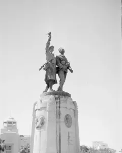 Demba et Dupont monument showing two military figures atop a tall stone pedestal with plaques and inscriptions.