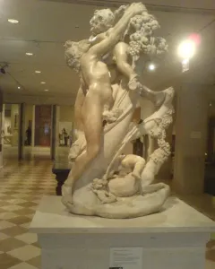 Marble sculpture of A Faun Teased by Children showing a muscular nude figure reaching up toward grapes and a child, with another child near the base.