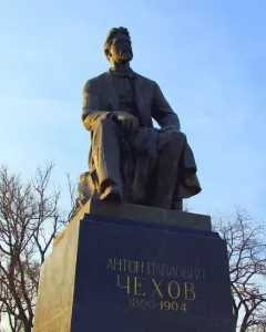 Chekhov Monument, a bronze seated statue of a bearded man on a pedestal against a blue sky