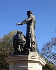 Emancipation Memorial bronze statue with Abraham Lincoln standing beside a kneeling figure on a stone pedestal.
