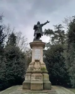 Monument to Columbus showing a bronze figure in period attire pointing outward on a tall stone pedestal.