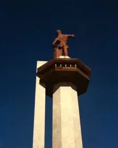 Vulcan statue atop a tall concrete pedestal against a dark blue sky.
