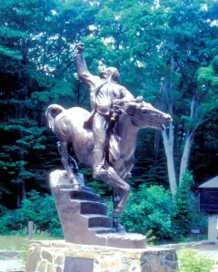 Israel Putnam equestrian statue of a man on horseback with one arm raised, set on a stone base amid trees and greenery.