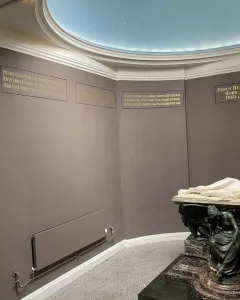Shelley Memorial with a white marble reclining male figure on a sarcophagus, supported by a seated bronze figure.