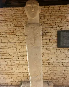 U Nativu stone bust against a dry-stone wall