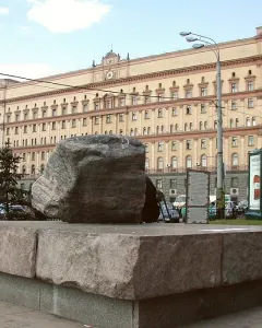 Solovetsky Stone monument, a large granite boulder on a stone base, with a beige building in the background.