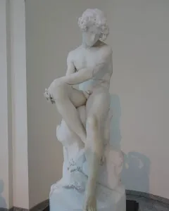 The Exiled, a white marble sculpture of a seated nude male figure with curly hair and a downcast expression.