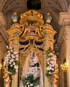 Madonna dell\'Udienza sculpture of the Madonna and Child displayed in a gilded shrine with flowers and crowns.