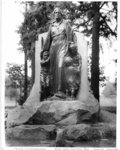 Pioneer Mother Memorial statue of a woman with three youths holding her garments, set on a rocky base with a fountain below.
