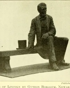Bronze Seated Lincoln sculpture of Abraham Lincoln seated on a long bench with a top hat beside him.