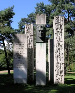 Julius Fučík Memorial with five stone pillars, including a central pillar with a metal bust and carved inscriptions.