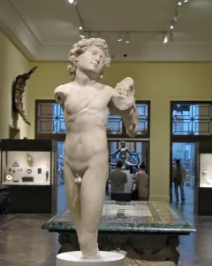 Incomplete marble statue of the Young Archer, showing a nude youthful male figure with curly hair and a diagonal band across the torso.