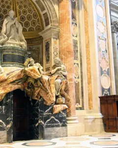 Tomb of Pope Alexander VII with a praying figure, white marble allegorical statues, and a dramatic draped canopy above a doorway.