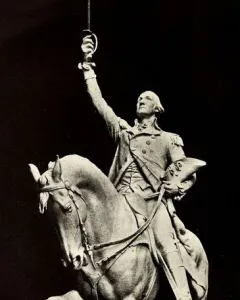 Monochrome statue of George Washington on a rearing horse, holding a raised sword and a hat.