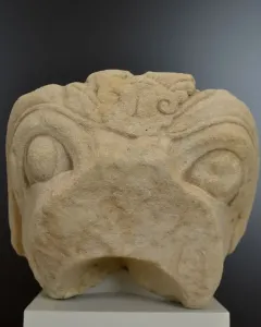 Grifo de Redován stone head sculpture with rounded eyes and a beak-like mouth on a pedestal.