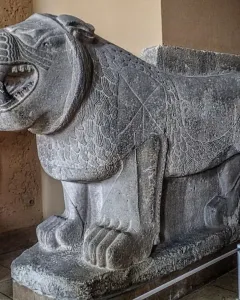 Weathered stone Sam\'al lion sculpture with an open mouth and carved mane