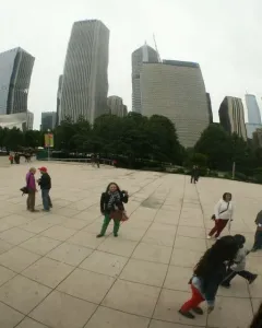 Cloud Gate reflects Chicago skyscrapers, trees, and people in the plaza.