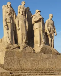 The Ghosts stone sculpture of several uniformed men on a stepped base with French lettering.