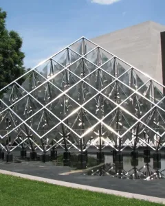 Delta Solar sculpture with reflective triangular panels rising above a dark pool of water.