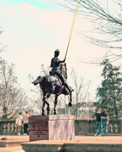 Joan of Arc equestrian statue with a raised yellow lance in a park setting