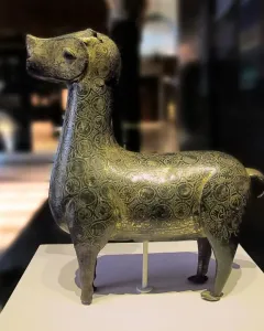 Stylized metallic deer sculpture from Madinat al Zahra on a white pedestal.