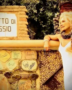 Decorated stone wall of the Muretto di Alassio with a sign at the top and ceramic tiles covered in signatures and sketches.