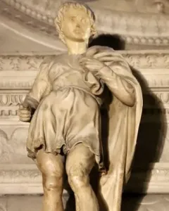 Marble statue of Saint Proculus standing in a short tunic and cloak among ornate stone carvings.