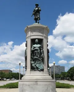Victory Monument in Chicago with a bronze soldier statue atop a tall stone monument and figures in recessed niches below.