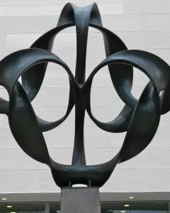 Continuum sculpture with dark metal looping ribbons forming circular openings.