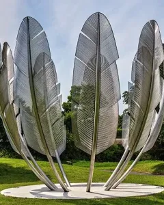 Kindred Spirits sculpture with tall silvery feather-like forms arranged in a circle on a grassy lawn.