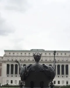 Alma Mater, a bronze seated female figure holding an open book and scepter on a stone pedestal outside Columbia University.