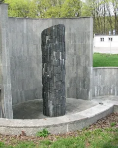 Monument of Common Martyrdom, a tall dark pillar of irregular blocks within a curved stone enclosure.