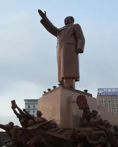 Long Live the Victory of Mao Zedong Thought monument with a raised-arm bronze figure on a pedestal and smaller figures around the base