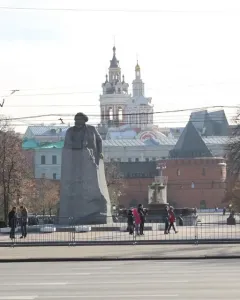 Monument to Karl Marx in a Moscow plaza, with a large stone statue on a rough base near trees and surrounding buildings.