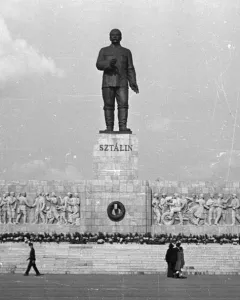 Stalin Monument in Budapest with a towering statue on a large pedestal and socialist realist bas-reliefs below.