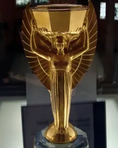Jules Rimet Trophy replica with a winged female figure holding a cup overhead on a dark base.