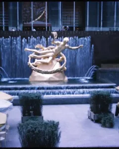 The Prometheus sculpture at Rockefeller Center, shown as a golden reclining figure holding up a ring above a tiered fountain.