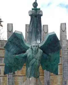 Monumento a Franco with a robed figure holding a cross-hilt sword above a winged figure on a stone base.