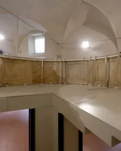 Reconstructed structure of the Pulpit of Prato Cathedral with a curved paneled railing inside a vaulted room.