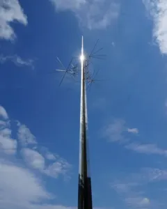 Ad Astra sculpture with a tall metallic spire and radiating spikes against a blue sky.