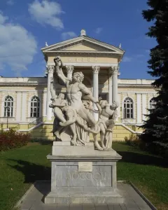 Laocoön sculpture of three figures entangled with serpents on a tall stone pedestal
