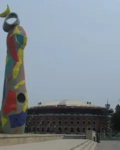 Dona i Ocell sculpture in Barcelona, covered in colorful mosaic tiles with a yellow crescent and ring at the top.
