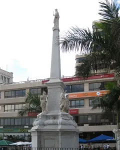 The Triumph of the Candelaria obelisk rises in an open plaza, with stone figures at the base and a white figure atop the monument.