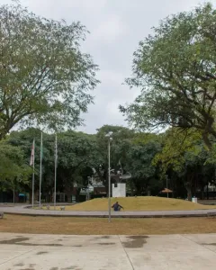 Ayrton Senna Monument on a raised grassy mound in a park, with a paved circular path and trees around it.