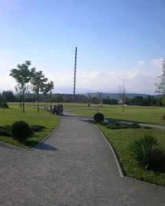 The Endless Column rises above a green park with trees, paths, and distant mountains.