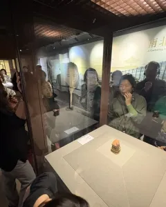 Meat-Shaped Stone displayed in a glass case with layered reddish-brown, pale, and dark stone bands.